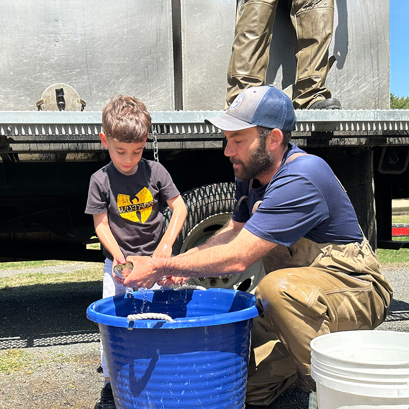 DEEP Biologist showing a trout to a child.